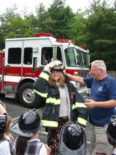 Fire Prevention Captain Don Costello helps a teacher don IFD turnout gear during a visit to Immaculate Conception School in Irvington, May 2004.